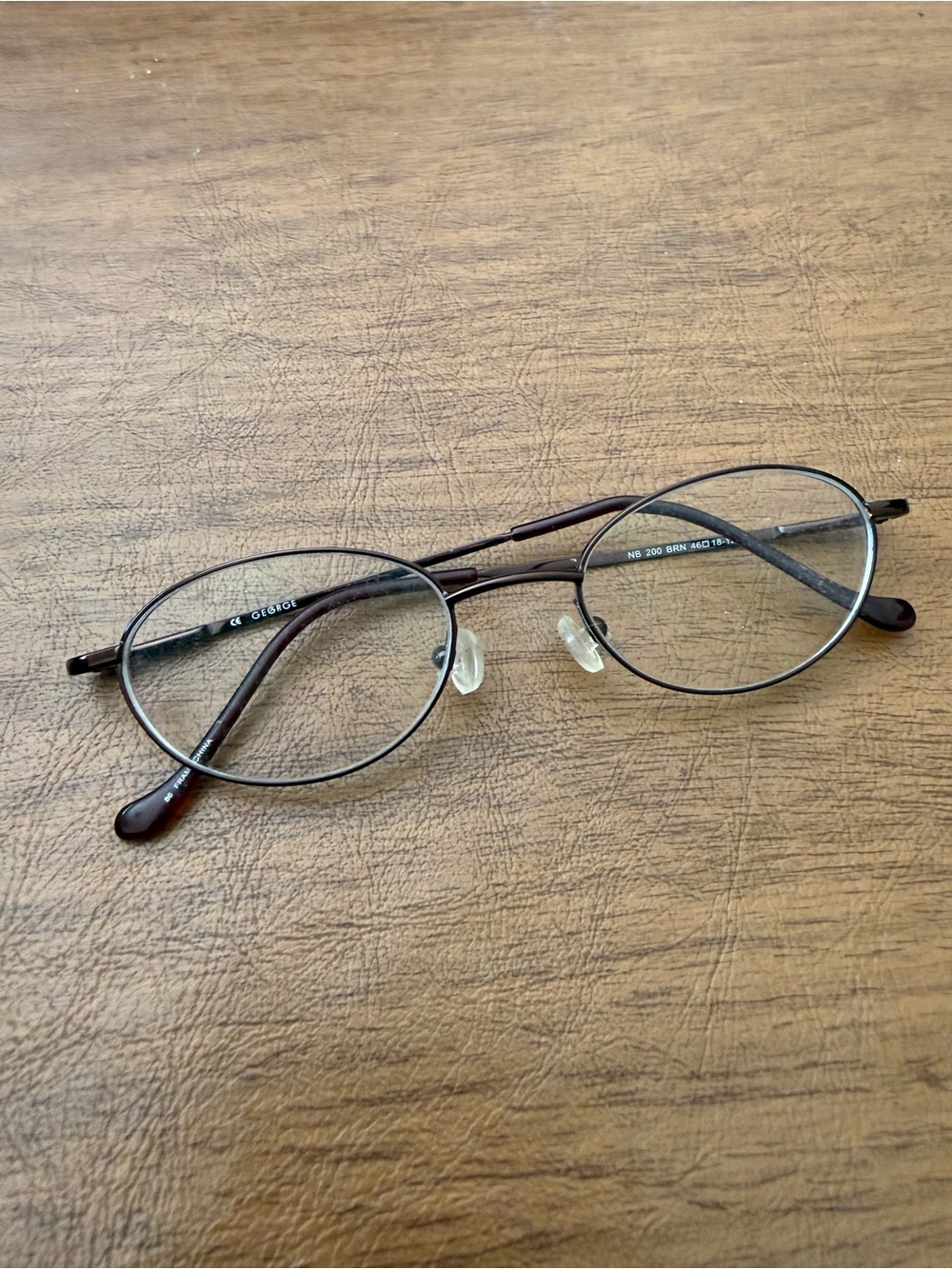 George NB 200 oval-shaped, full-rim metal frames in a brown finish